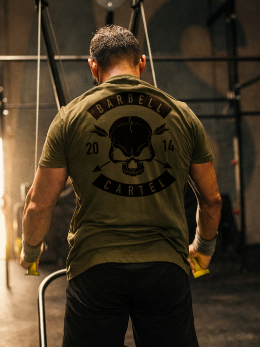 Man wearing a green t-shirt with a skull design and text in a gym setting